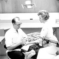 A black and white photo of a dentist and dental assistant in the 1960s working on a patient in a dental clinic